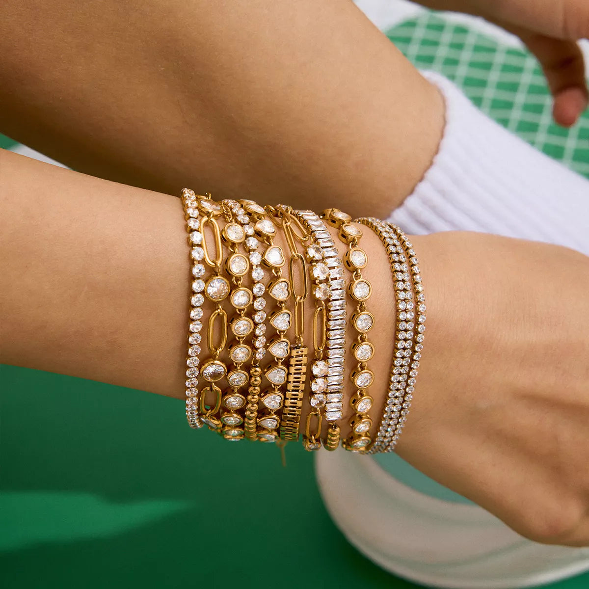 Gold-plated rhinestone chain bracelets stacked on wrist with round stone details