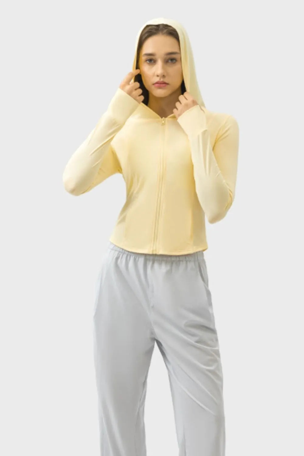 Light yellow zip-up hooded active jacket with long sleeves and hood up