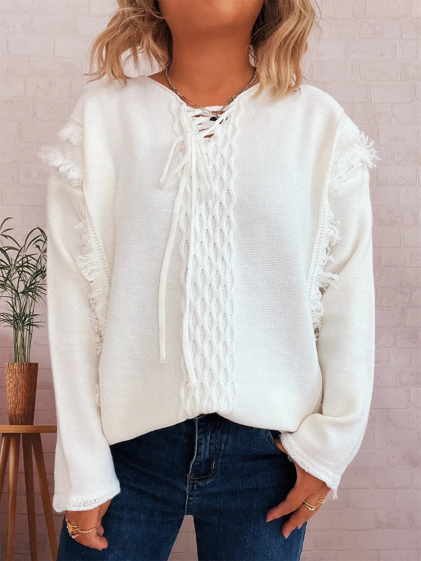 White raw-hem lace-up sweater with cable knit design and frayed cuffs