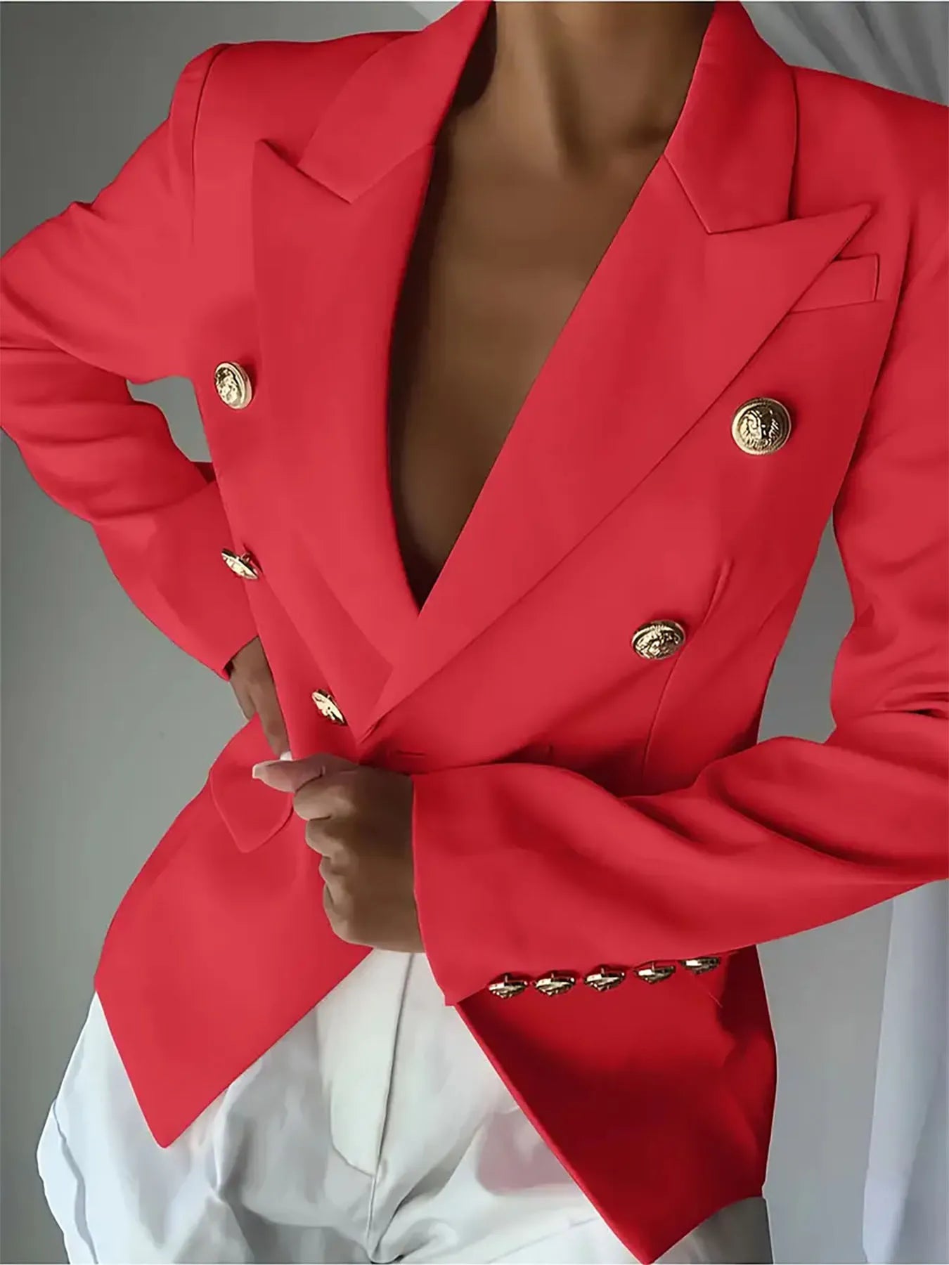 Red blazer with notch lapel, gold decorative buttons, and satin-like blouse underneath
