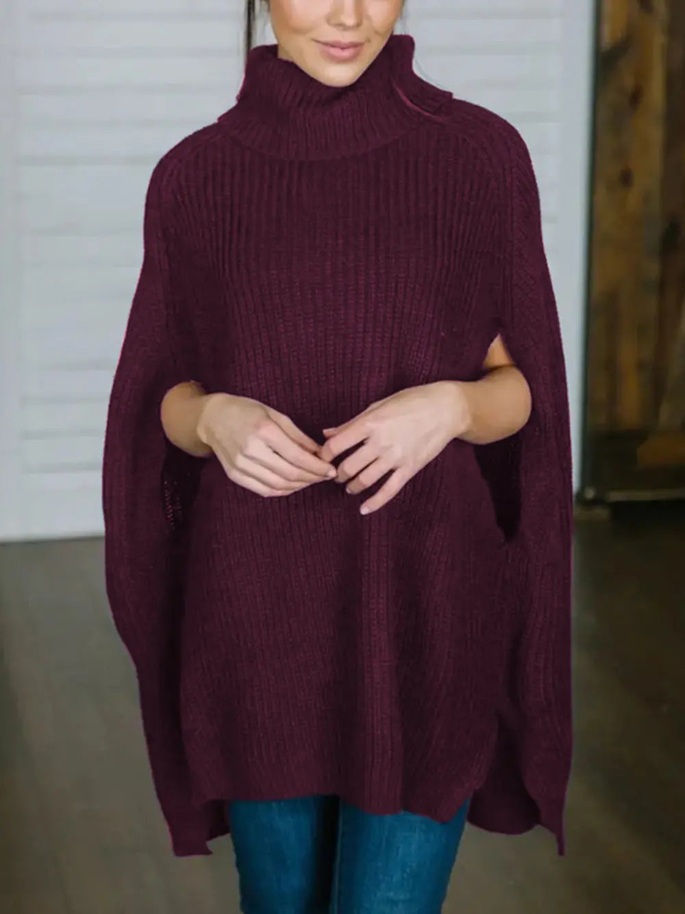 Burgundy turtleneck slit sweater with ribbed collar and loose drape, side slit at hem.