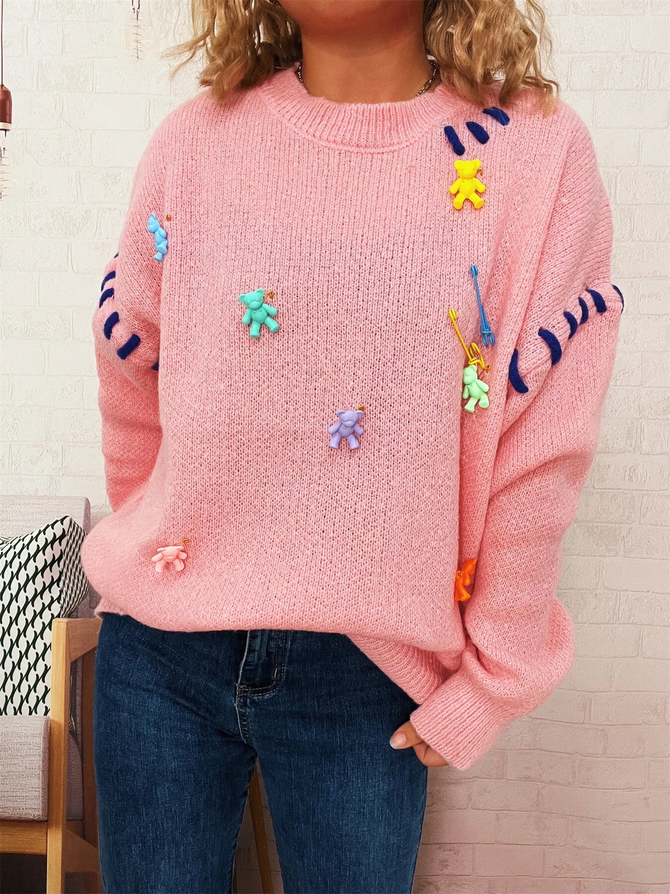 Pink round-neck knit sweater with colorful animal appliques on chest and long sleeves