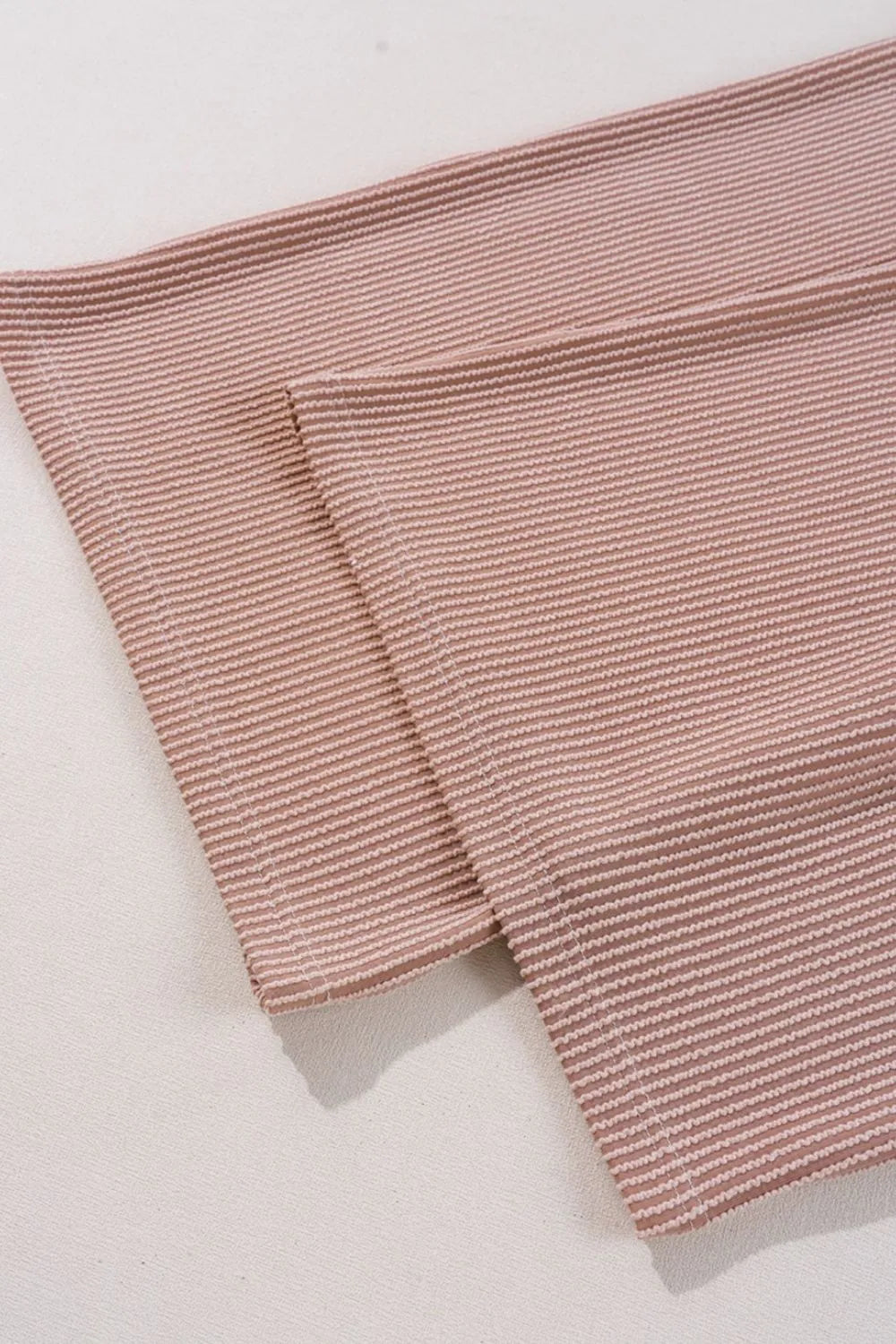 Close-up of dusty mauve striped corded fabric fold and stitched edge