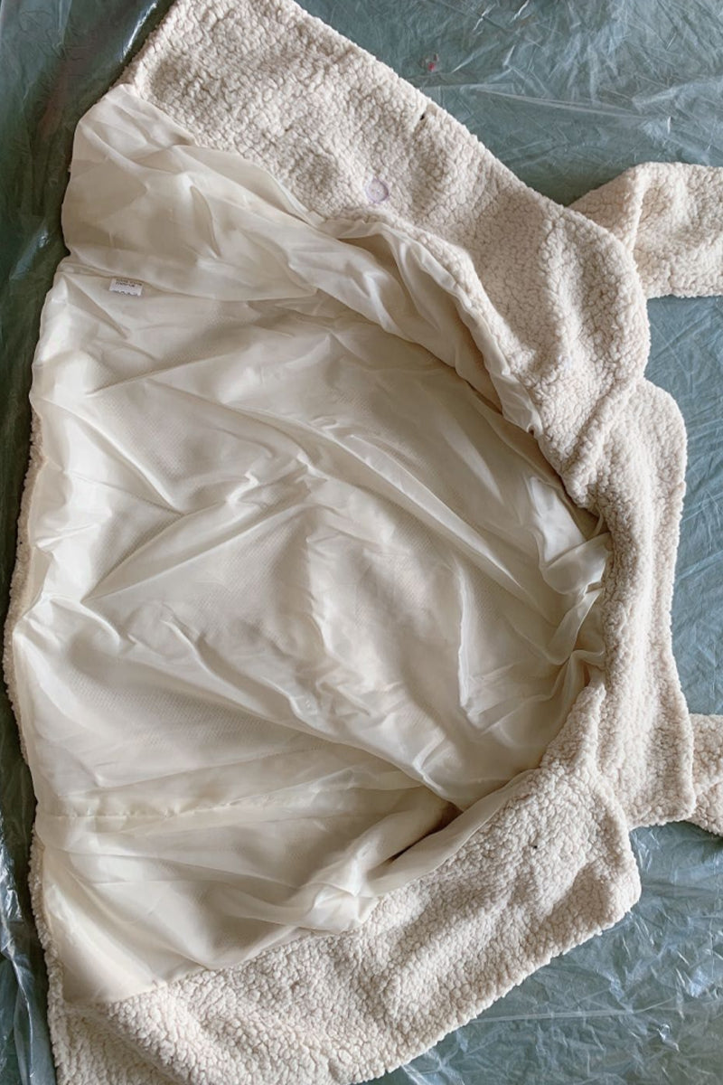 Cream sherpa coat lining and collar fabric detail, soft textured surface