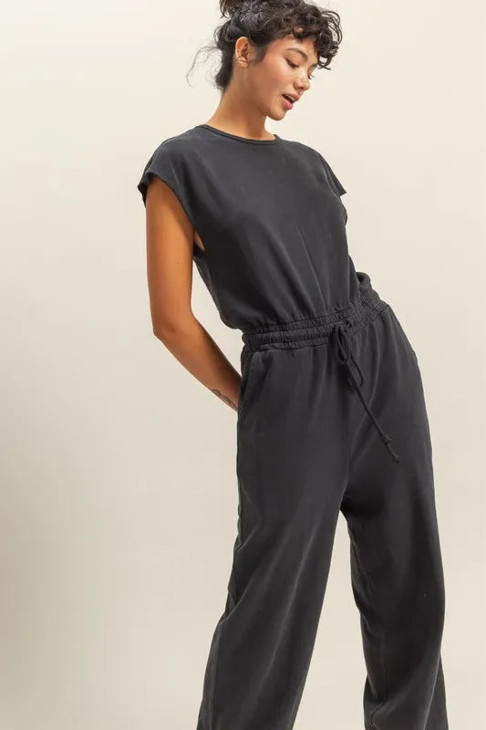 Black cap-sleeve jumpsuit with elastic drawstring waist and relaxed wide-leg legs.