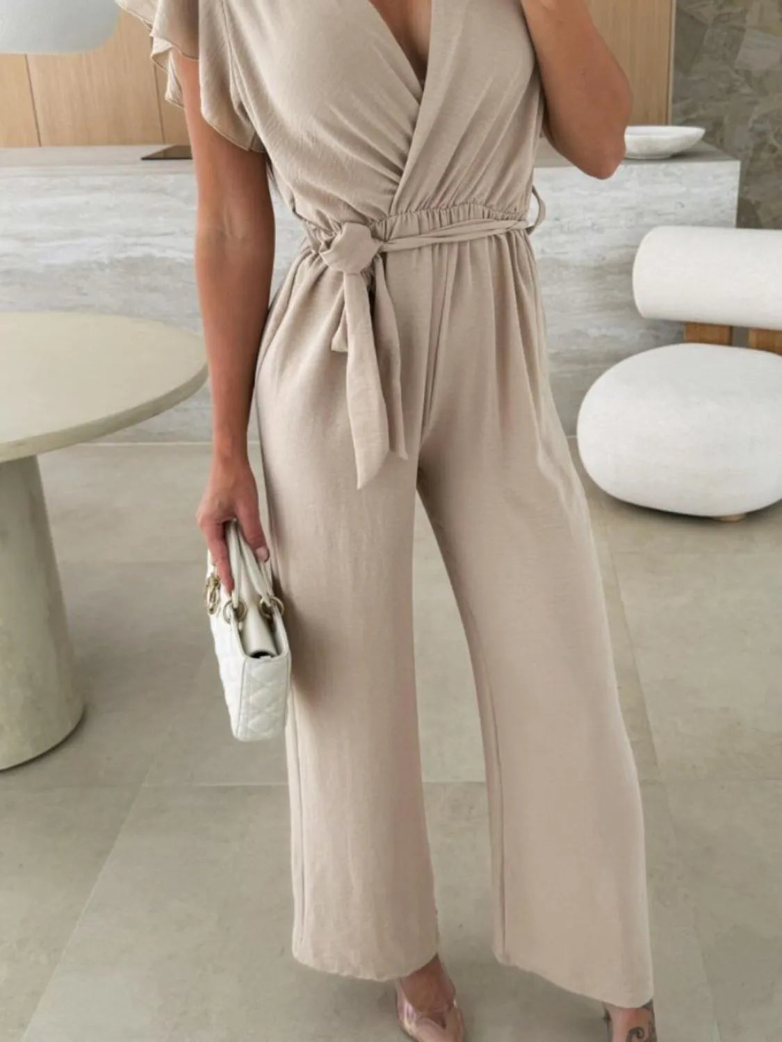 Tan wide-leg jumpsuit with tied waist belt and V-neck surplice bodice