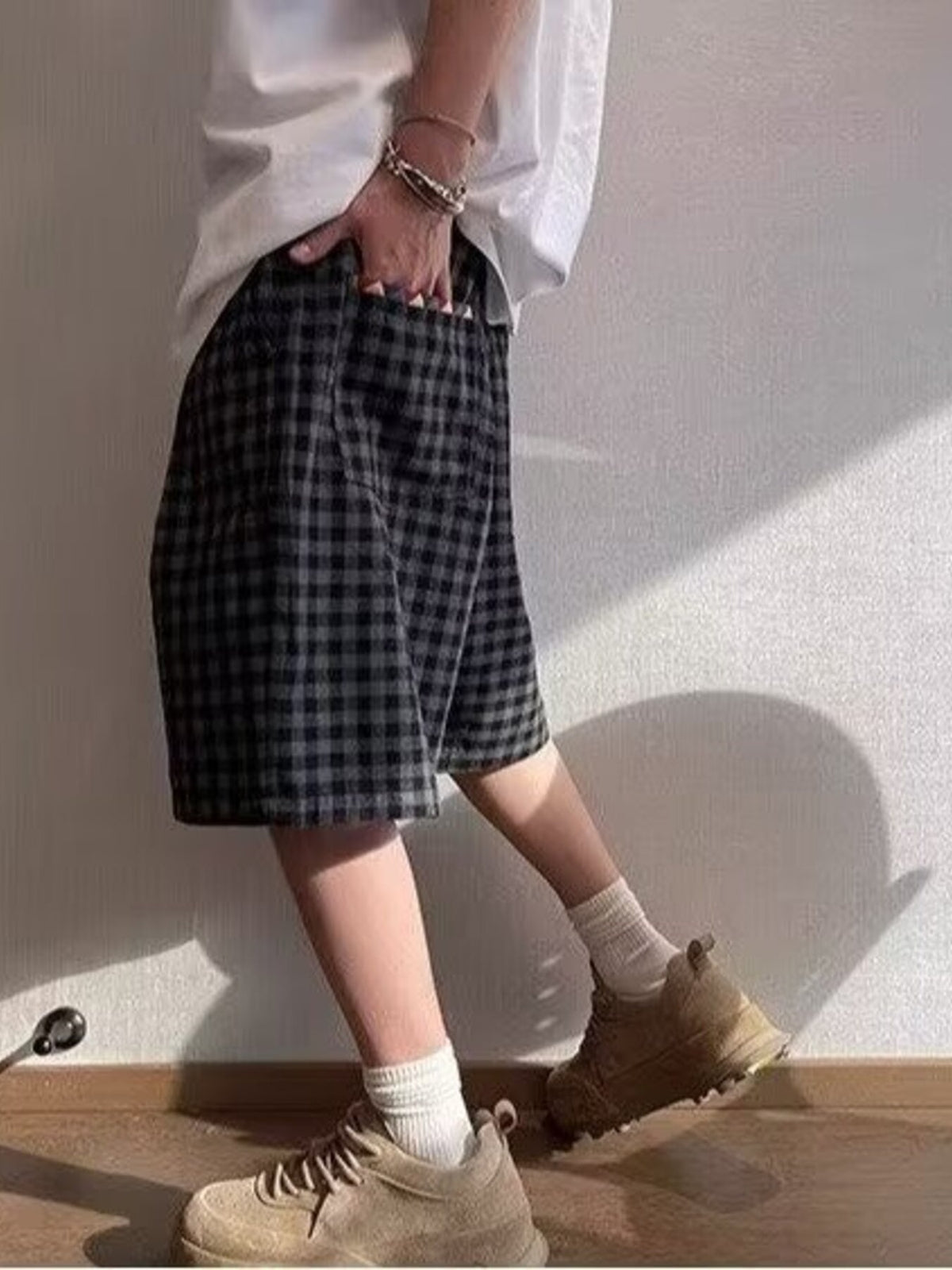 Dark plaid drawstring shorts with knee-length cut and multicolor tie strings, side view