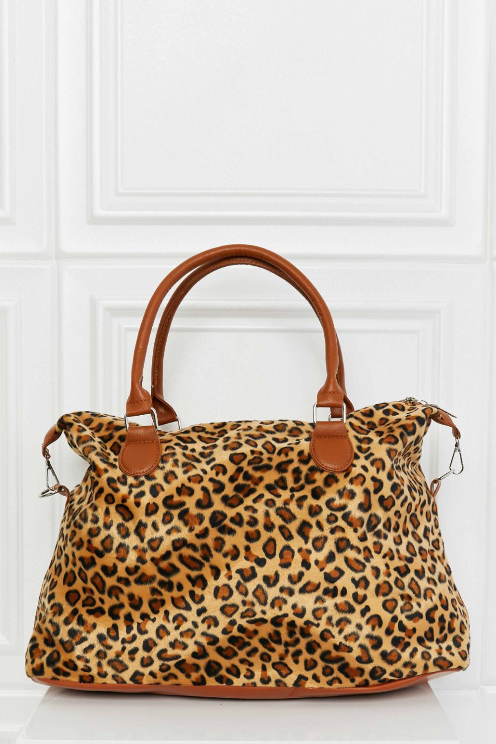 Leopard print weekender bag with tan top handles, side buckles, and zipper