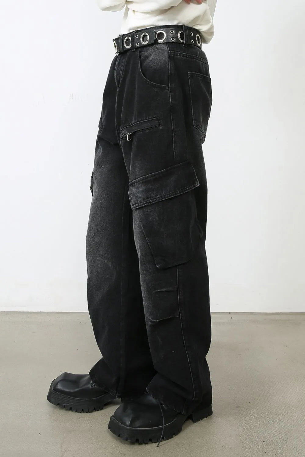 Dark baggy cargo jeans with stacked cargo flap pockets at the thighs and wide hem