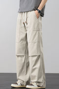 Beige loose cargo pants with drawstring waist and side cargo pockets, relaxed fit.