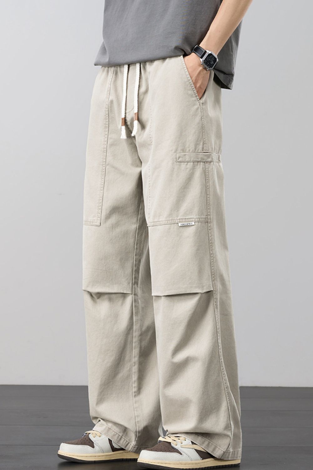 Beige loose cargo pants with drawstring waist and side cargo pockets, relaxed fit.