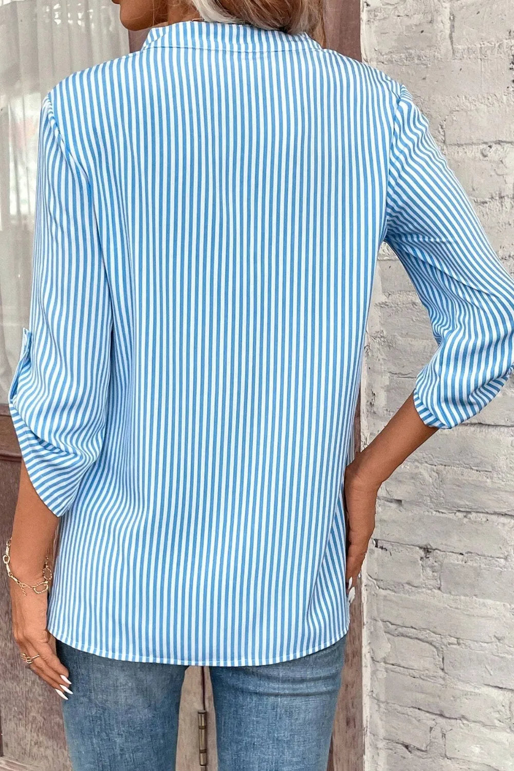 Light blue striped roll-tab sleeve shirt from the back, with vertical stripe pattern