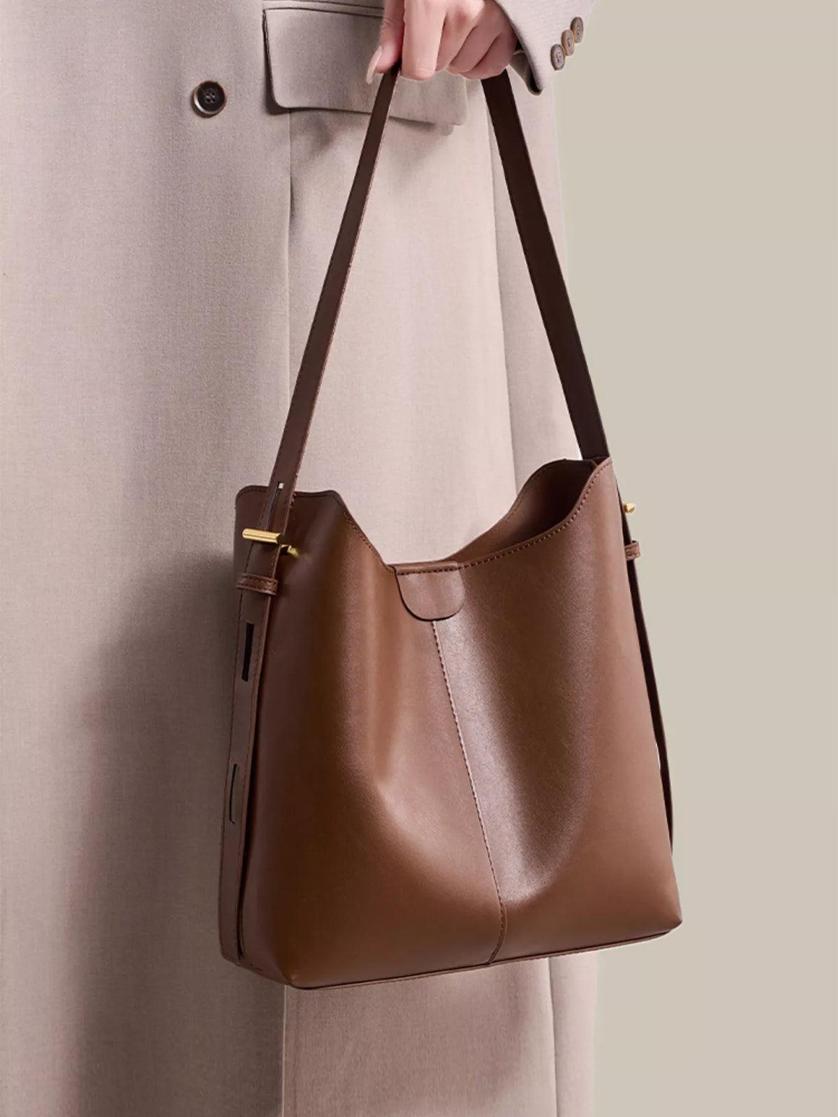 Brown medium shoulder bag worn on shoulder with adjustable strap and gold hardware