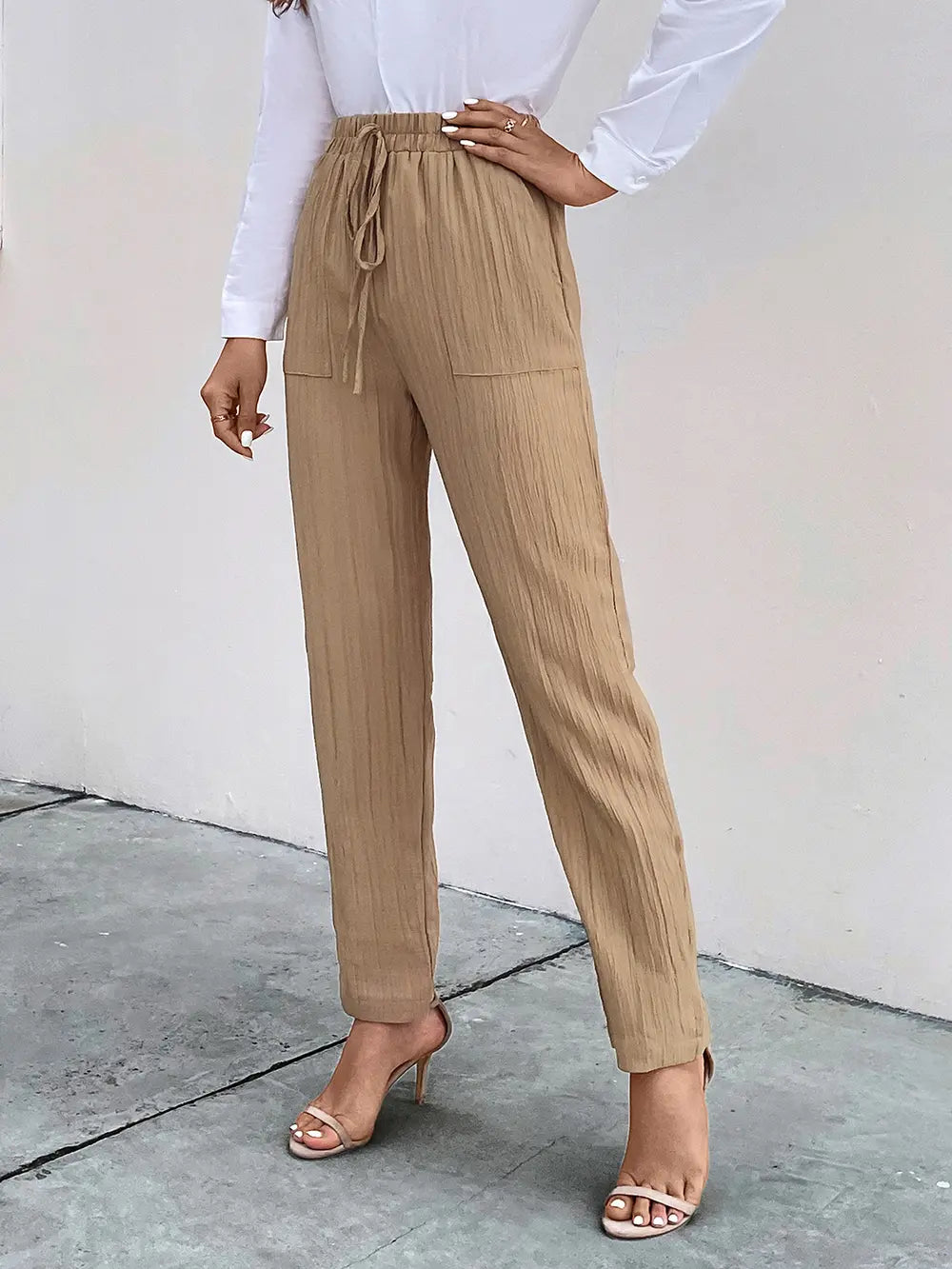 Tan textured drawstring pants with side pockets and tapered ankle silhouette