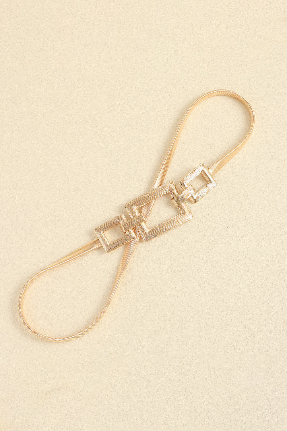 Gold belt with square buckle at center, loop-style strap with extra small squares