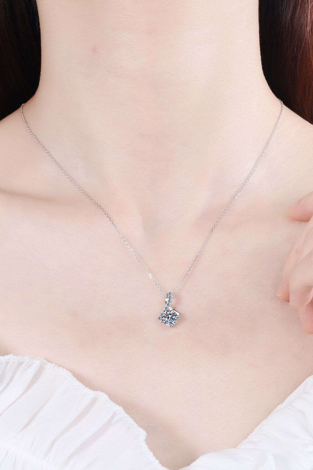 Silver moissanite pendant necklace on neckline, small heart-shaped prong-set pendant