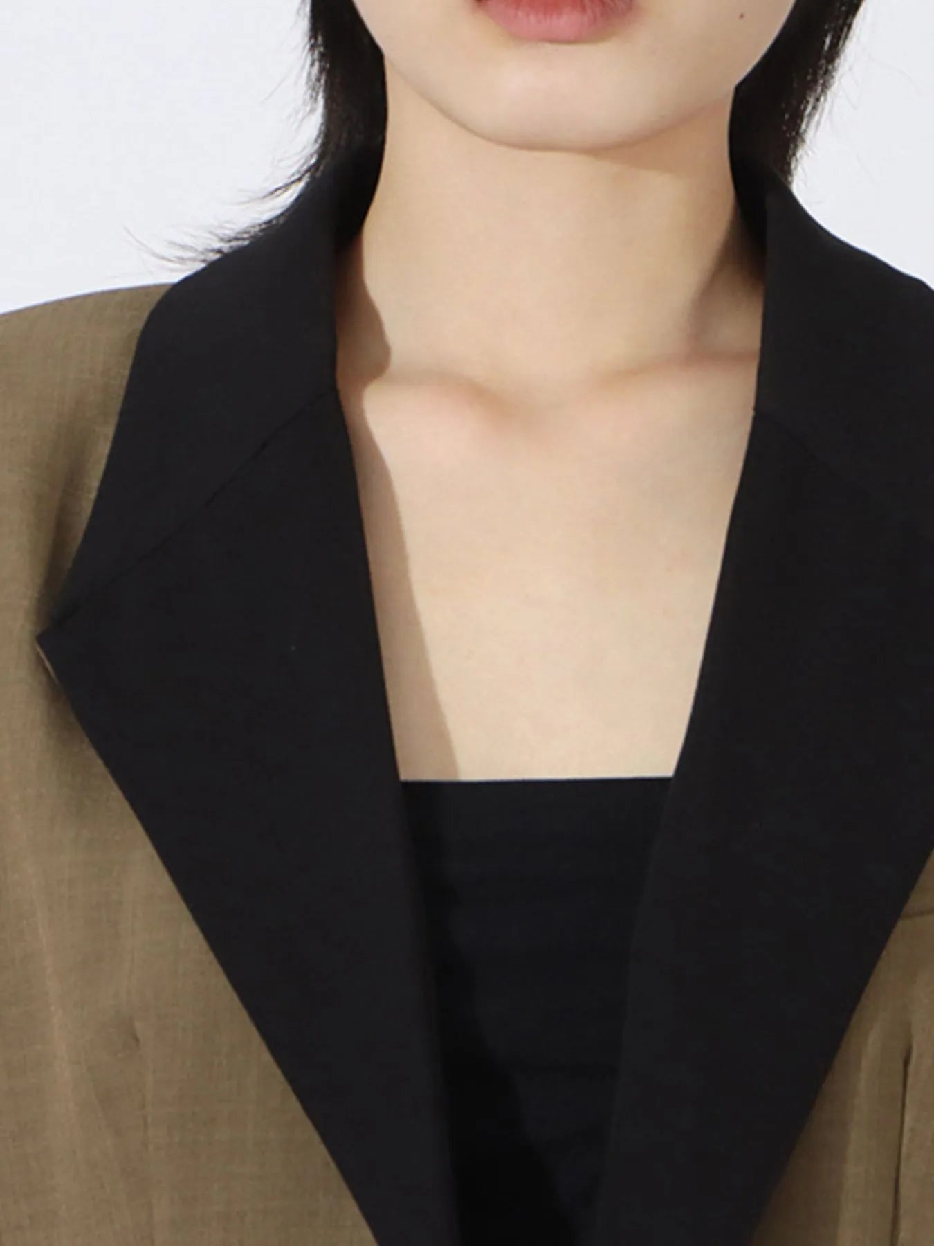 Black contrast lapel and neckline detail on a khaki green blazer with inner top visible