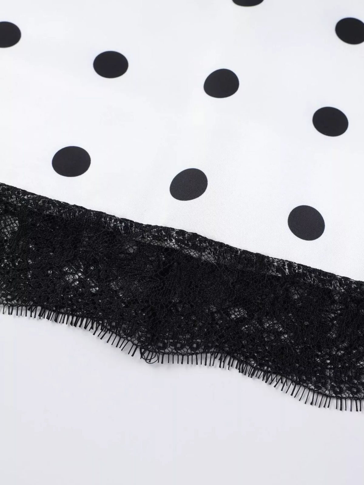 Black lace trim along the hem of a white polka dot skirt