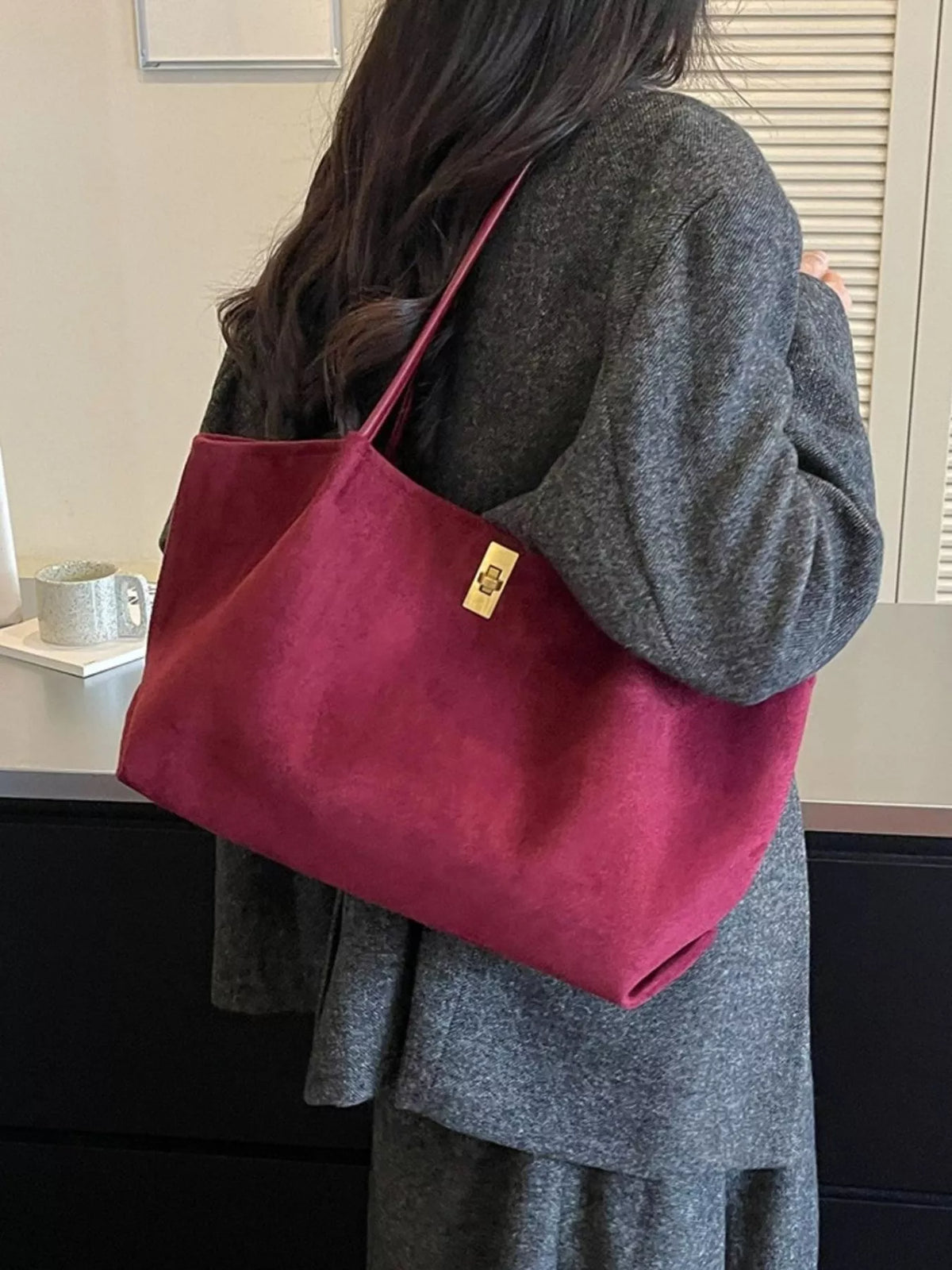Burgundy suede tote bag over shoulder, gold turn-lock clasp, red top handles