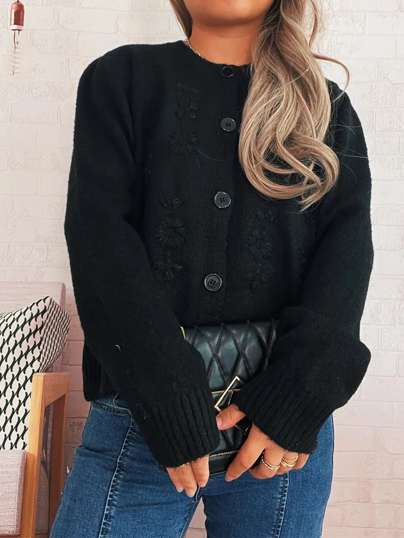 Black knit cardigan with flower embroidery, round buttons, and ribbed cuffs and hem.