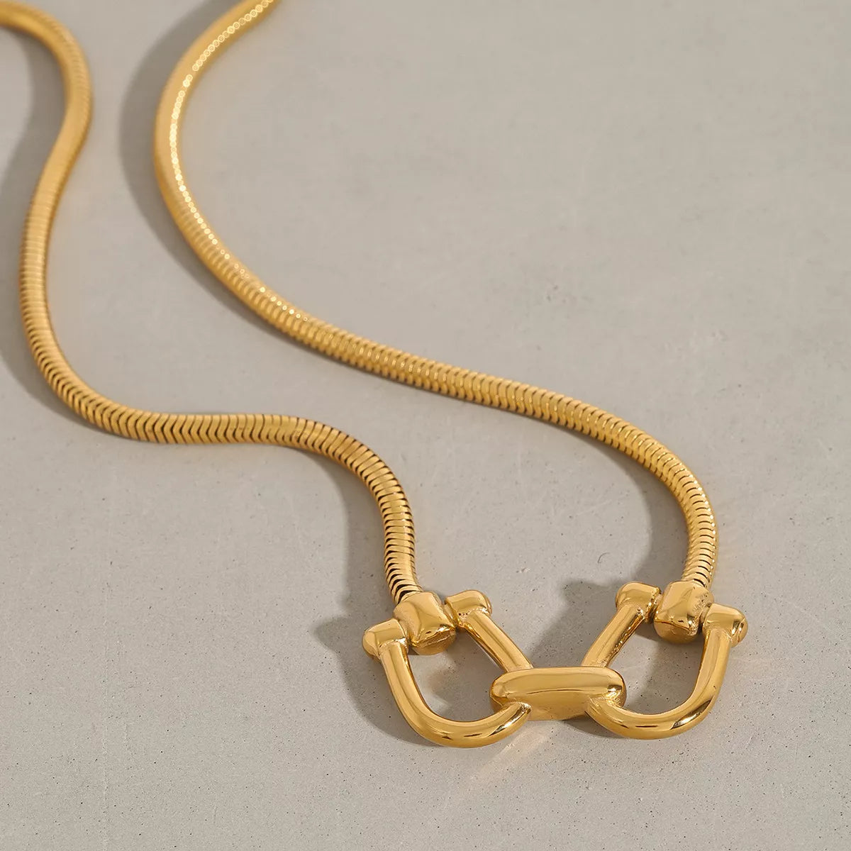 Gold-plated rope chain necklace with horseshoe-shaped linked clasp centerpiece
