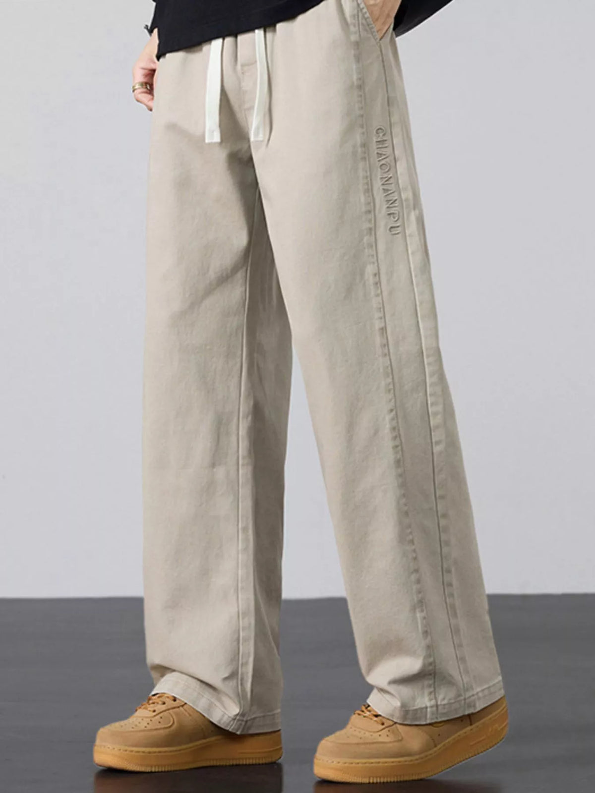 Men's wide-leg drawstring casual pants, light khaki with long relaxed legs and drawstring waist.