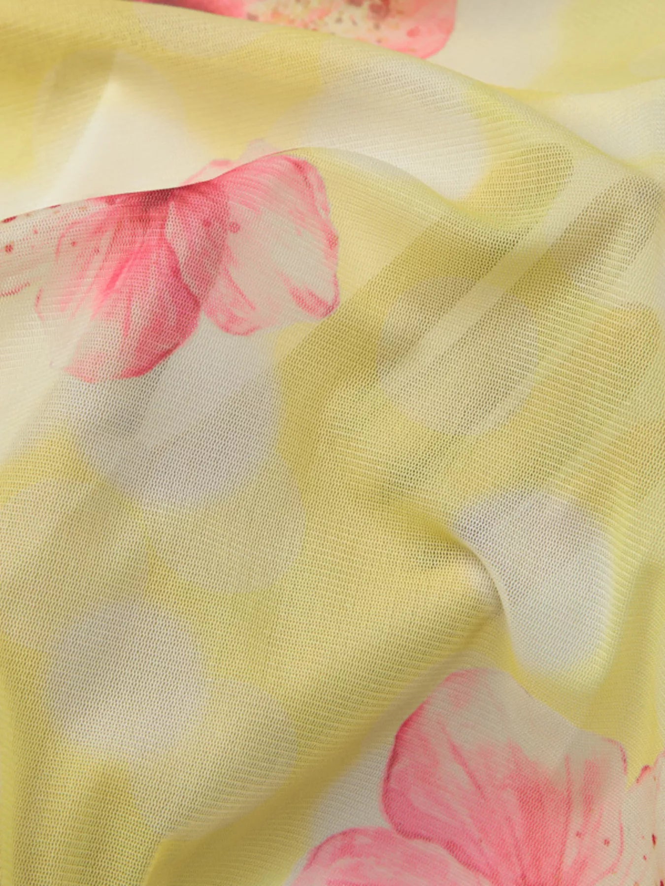 Close-up of yellow sheer fabric with pink flower print across soft mesh weave
