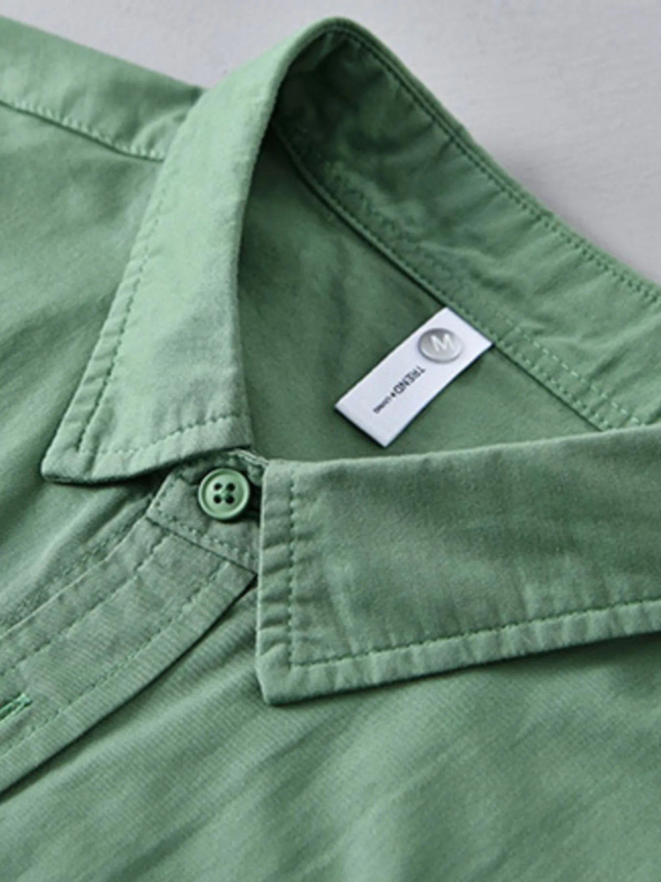 Green short-sleeve button-up shirt collar with button placket and tag
