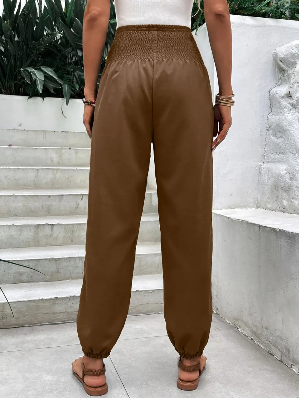 Brown smocked high-rise jogger pants with side pockets and elastic ankle cuffs