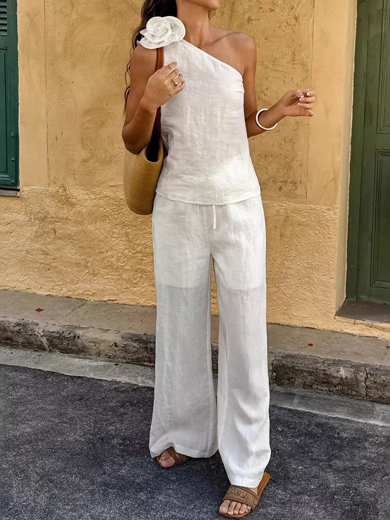 White one-shoulder top with floral detail and straight wide-leg pants