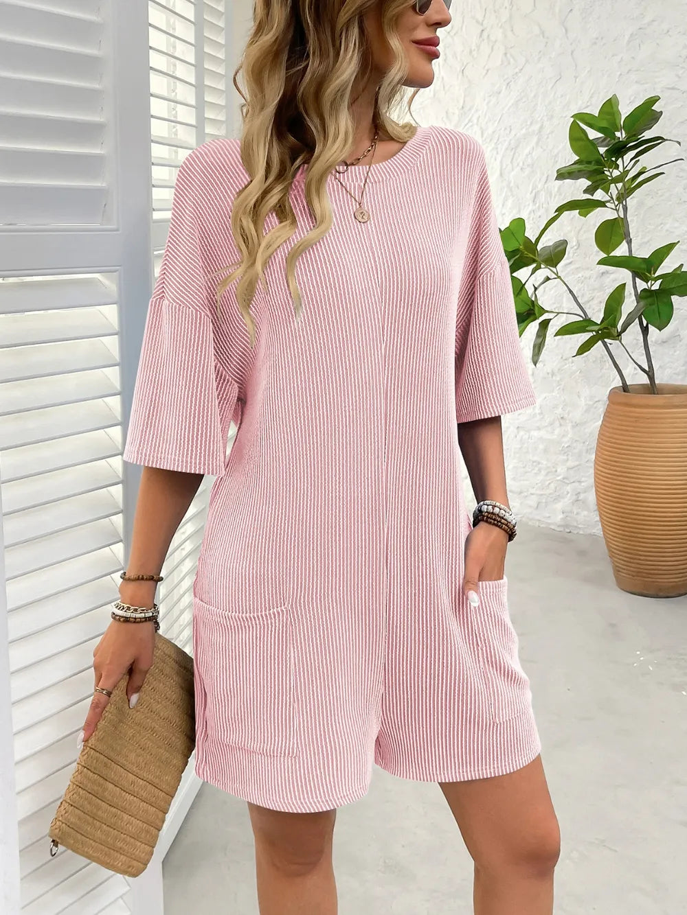 Textured pink romper with round neck, half sleeves, and front patch pockets
