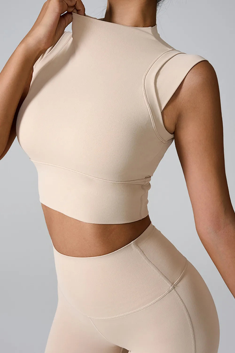 Cream mock neck active tank, sleeveless, fitted back view with seams.