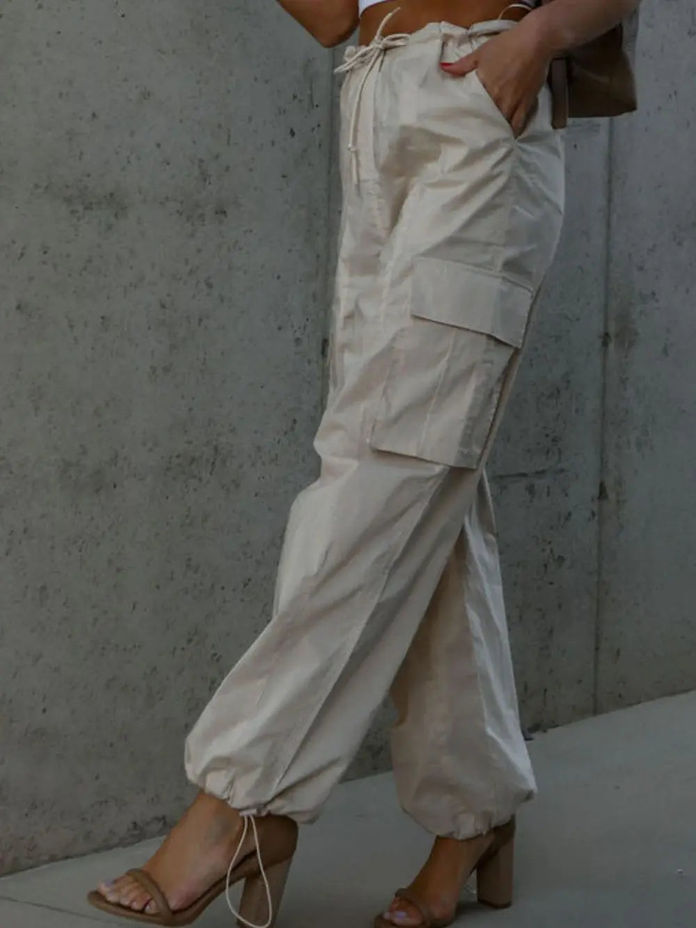 Beige drawstring cargo pants with patch pockets and cuffed ankles