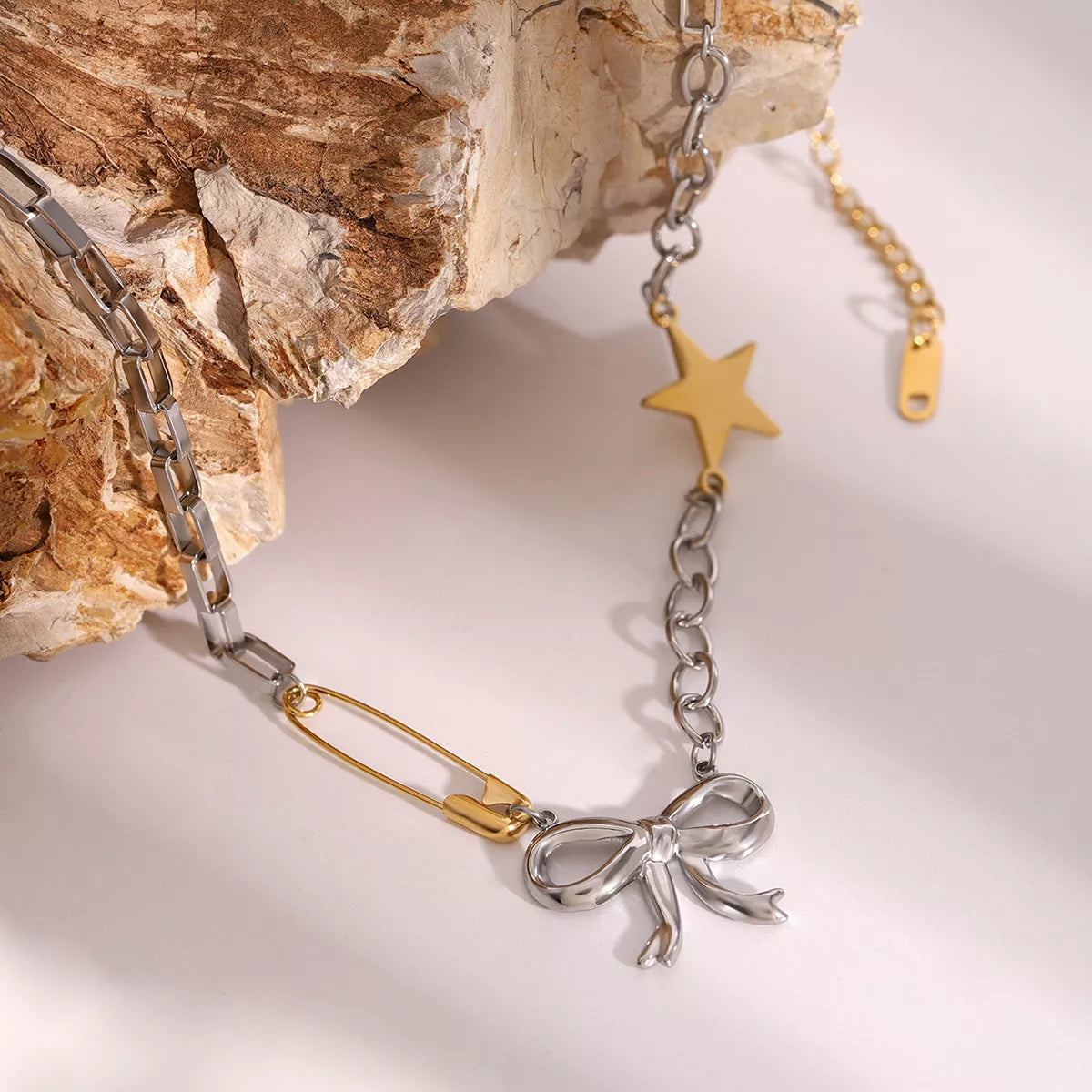 Two-tone star bow necklace with gold star charm, silver ribbon bow pendant, and mixed links