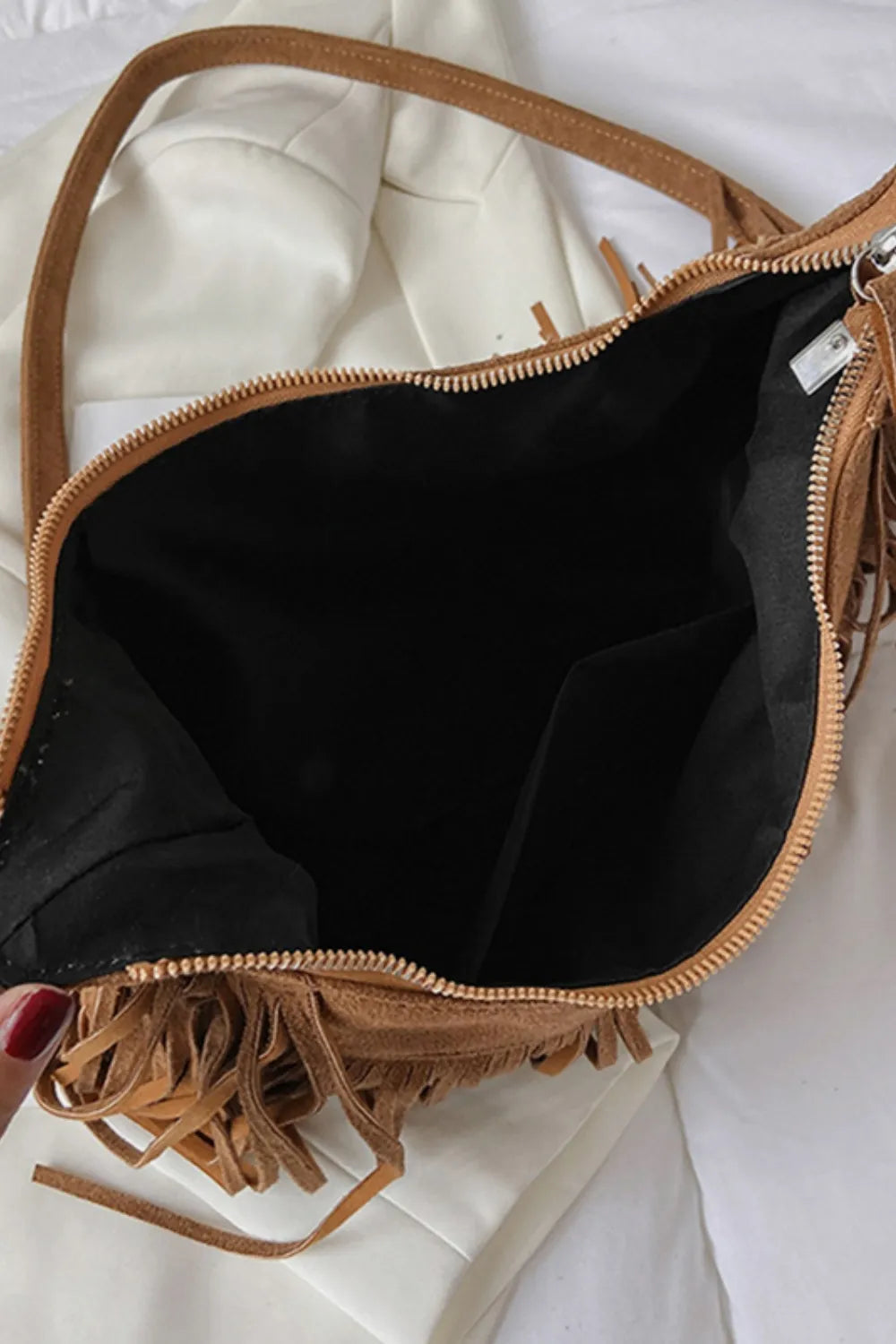 Tan suede shoulder bag interior visible with top zip and fringe tassels