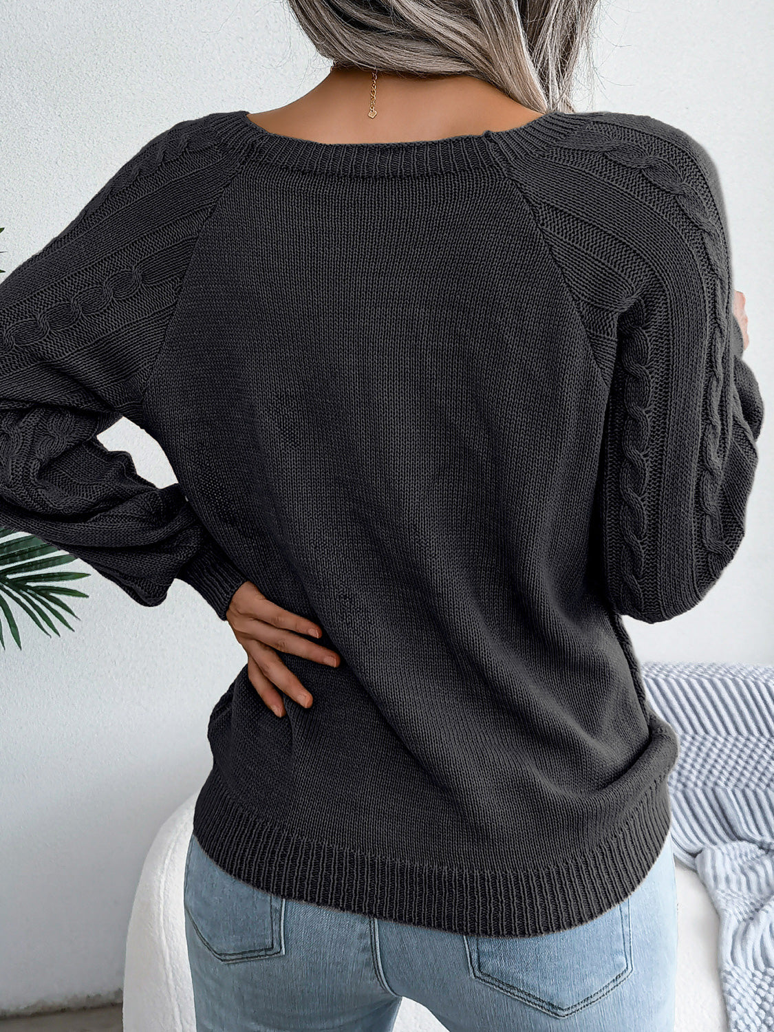 Black cable-knit sweater with diamond cable pattern, long sleeves, back view