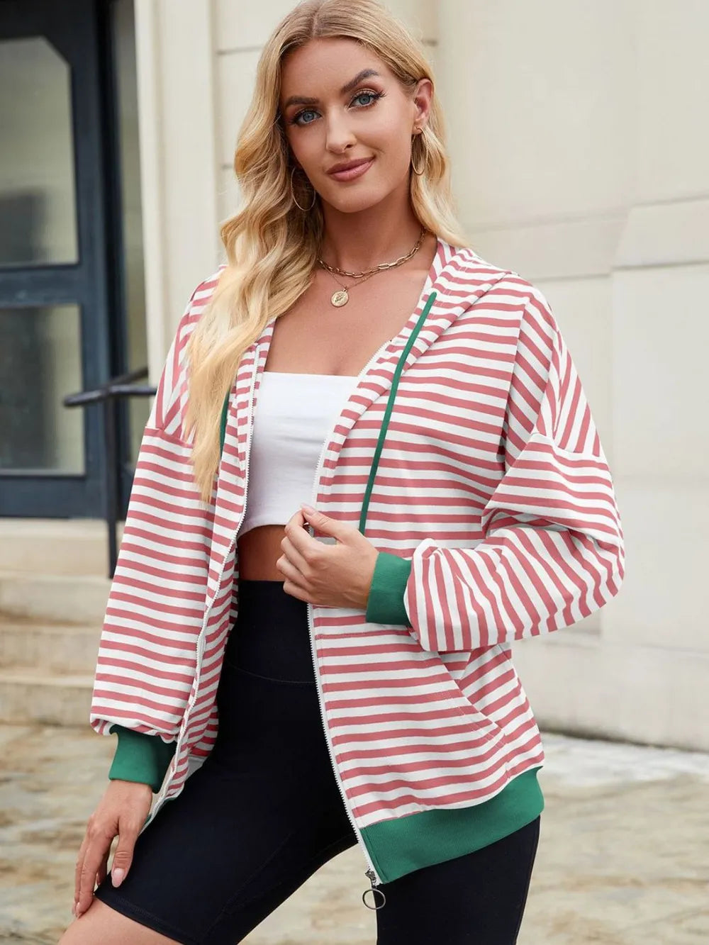 Pink-and-white striped zip-up hoodie with hood and drawstring, long sleeves.