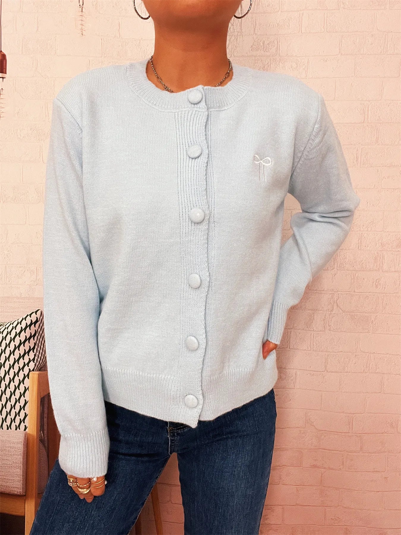 Light blue knit cardigan with round neck, long sleeves, and visible button placket