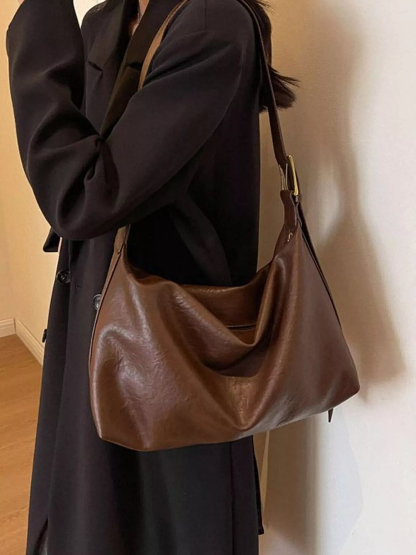 Adjustable-strap brown PU shoulder bag carried by a person in a black coat
