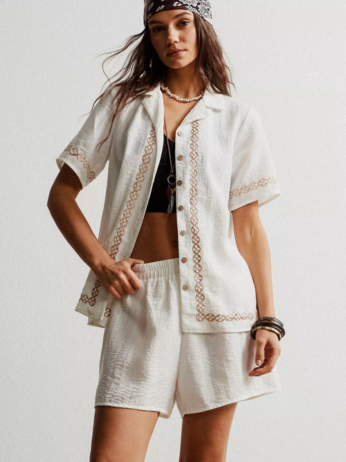 White embroidered short sleeve button-up shirt and matching shorts set, front view