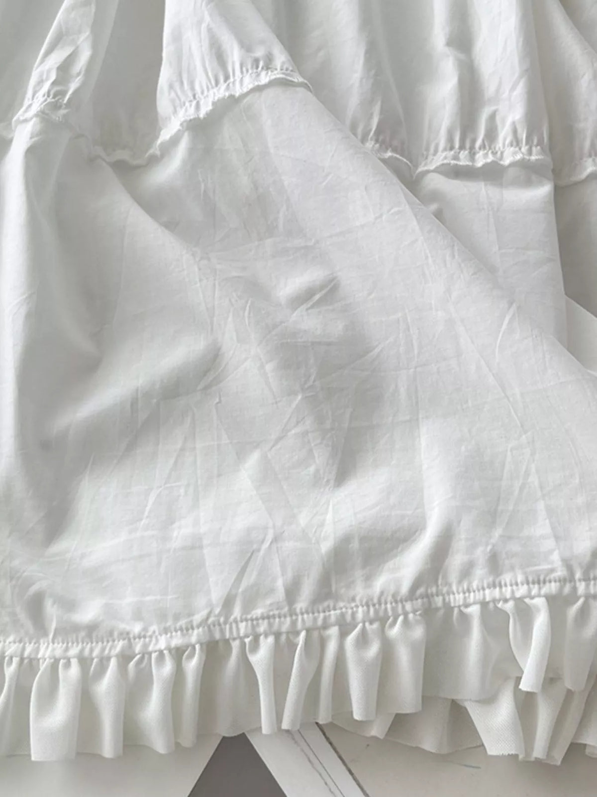 White tiered cotton maxi dress hem with gathered ruffle edge and layers