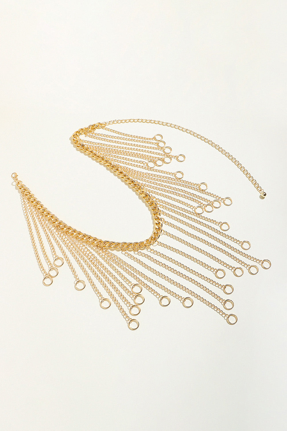 Gold chain fringe belt detail with oval ring center and long dangling charm links