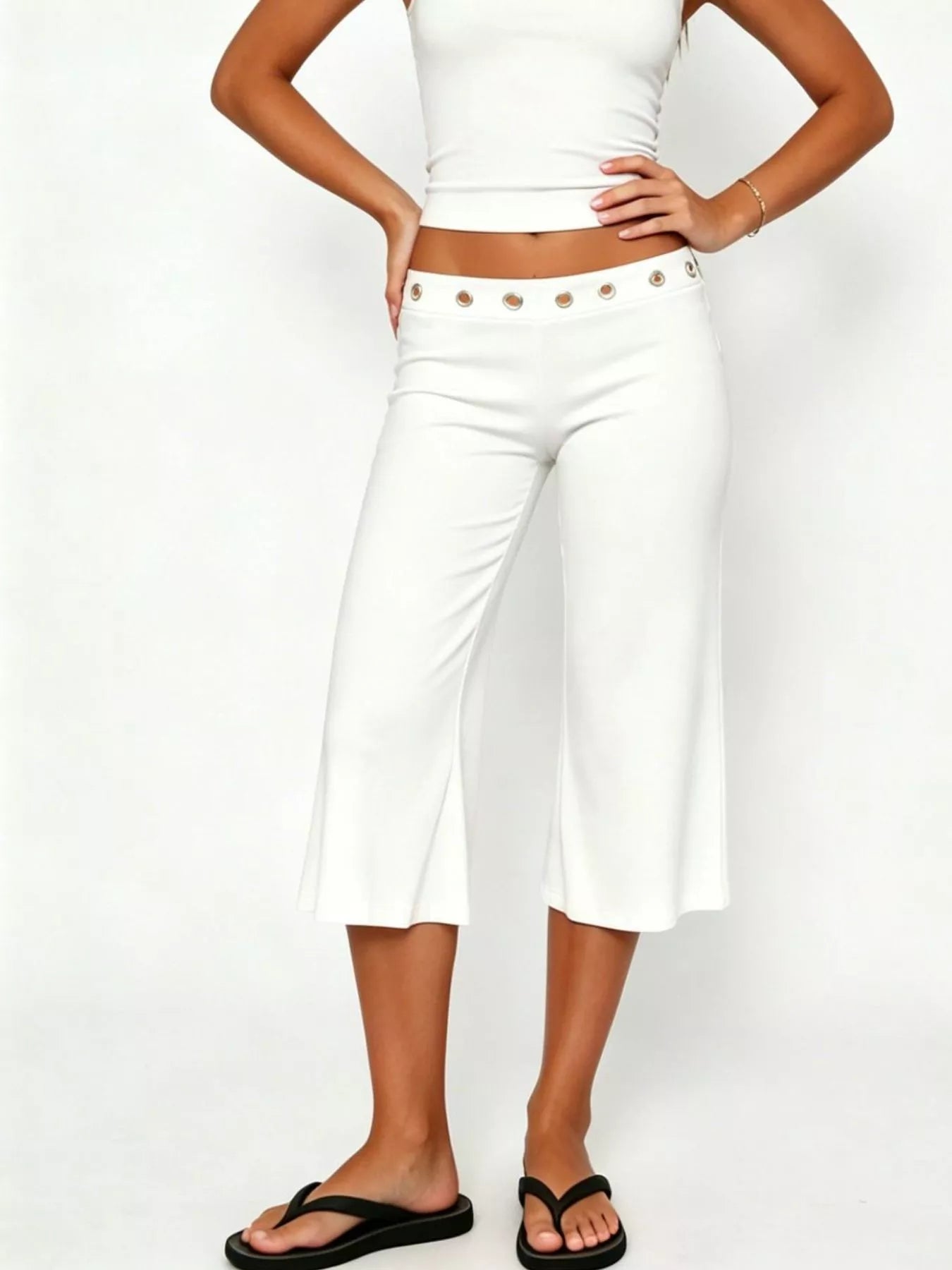 Mid-rise capri pants in white, eyelet button waistband, wide-leg flare at calf-length.
