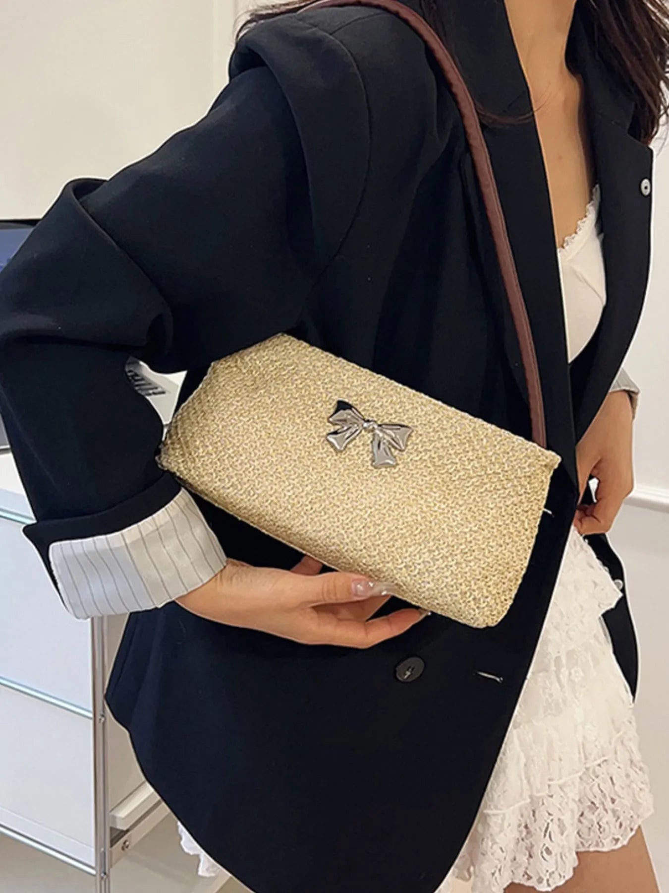 Woven straw shoulder bag with silver bow detail and brown strap, rectangular shape