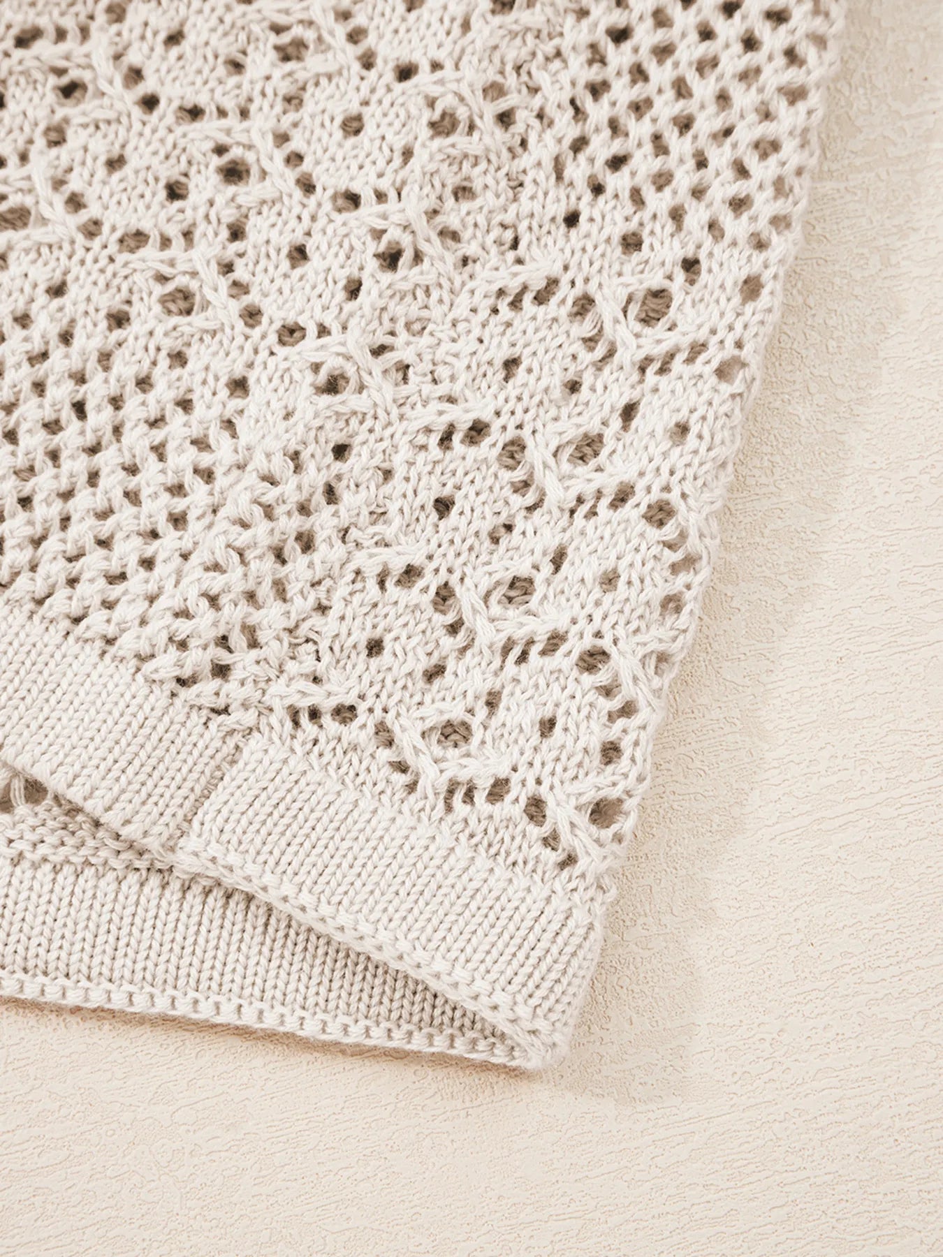 Beige hollow-knit fabric with openwork stitch pattern and ribbed bottom trim