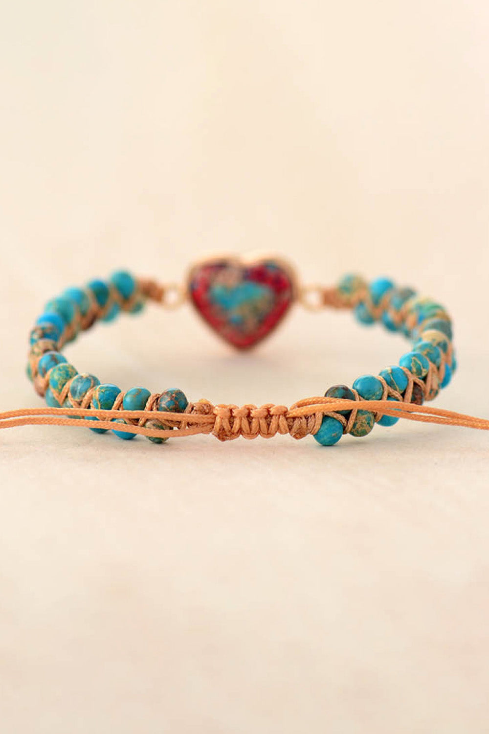 Turquoise braided bracelet with gold heart-shaped stone pendant and orange tie cord