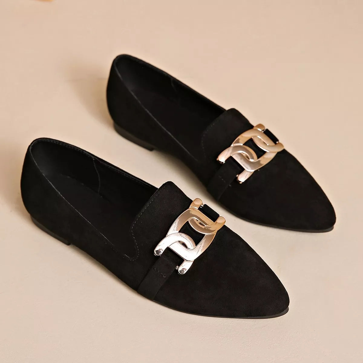 Pair of black suede pointed loafers with gold chain link buckle