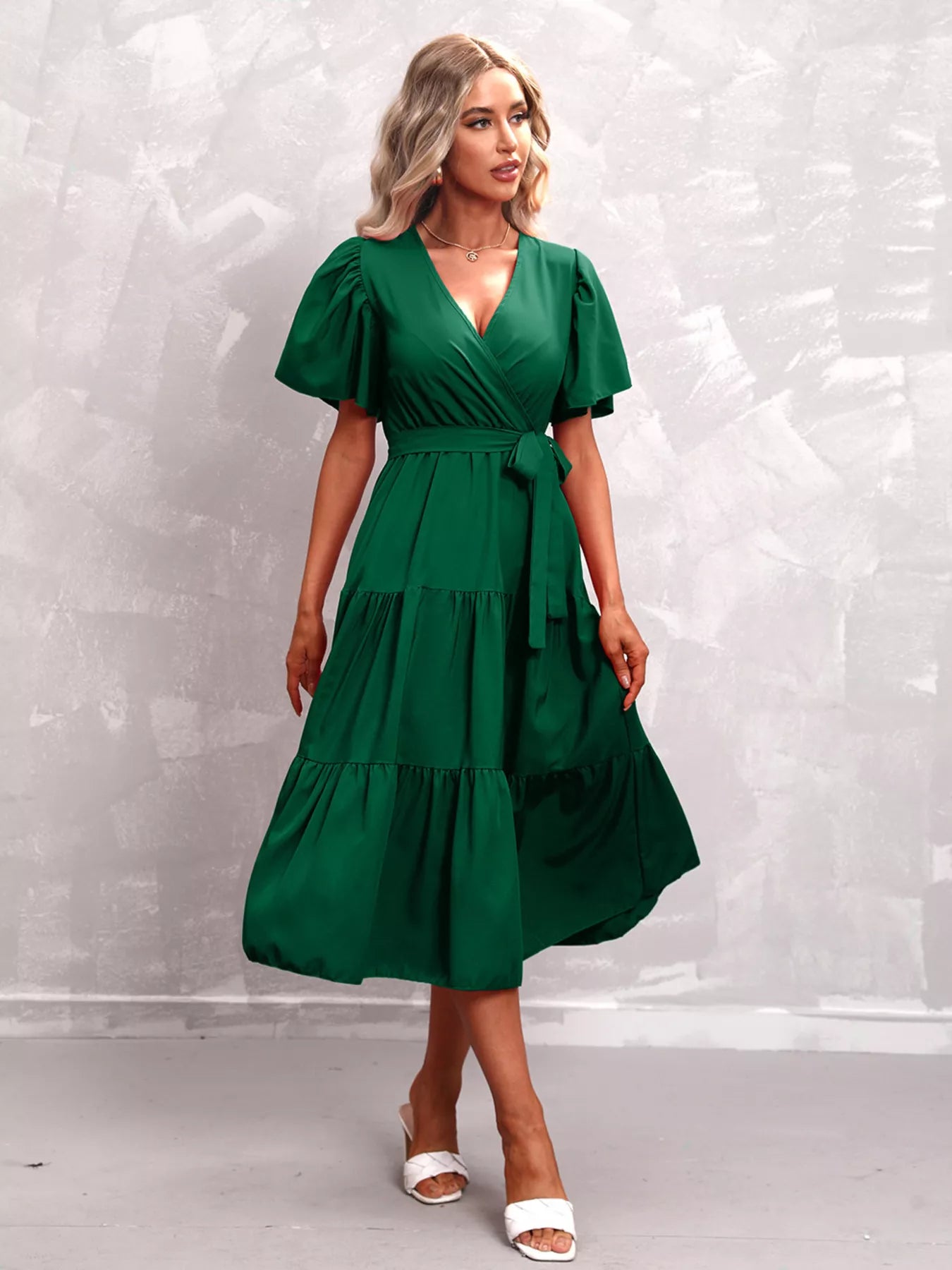 Deep green flutter sleeve tiered midi dress with V-neck and waist tie belt, front