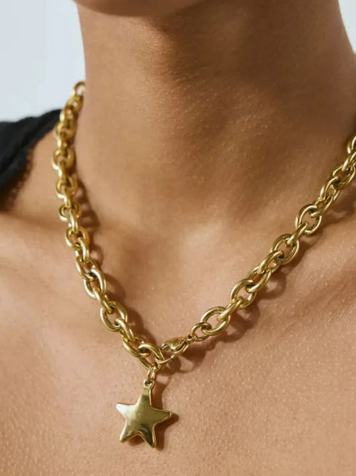 Gold chain necklace with dangling star pendant, oval links and star charm close-up