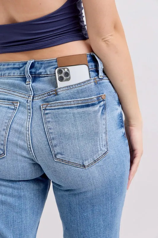 Close-up of light blue jeans with cell phone in front pocket and stitched front detail